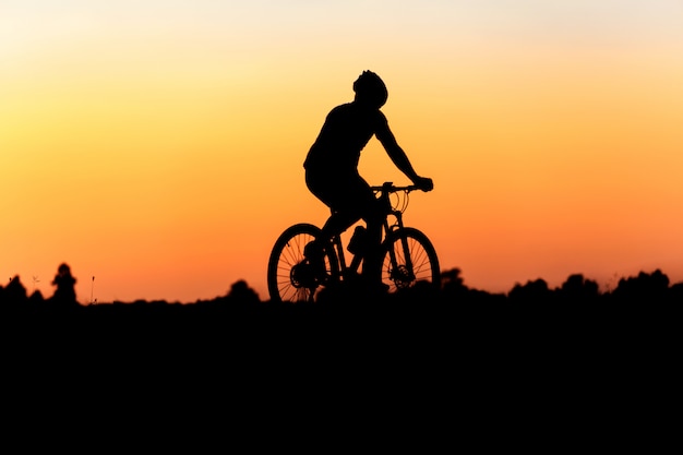 写真 美しい夕日の背景に動きのサイクリストのシルエット