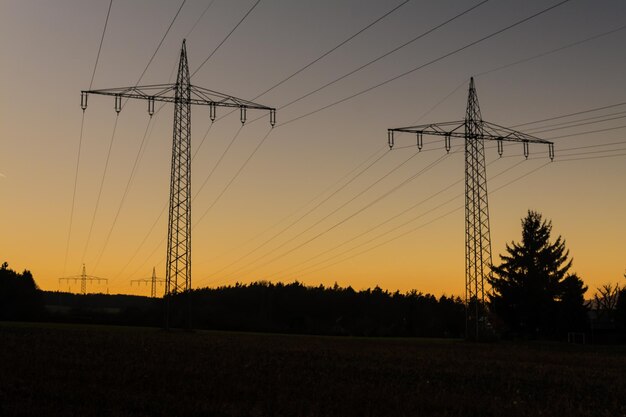 写真 夕暮れの空に照らされたフィールドの電気柱のシルエット