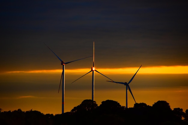 Фото Силуэт ветряной турбины на фоне неба во время захода солнца