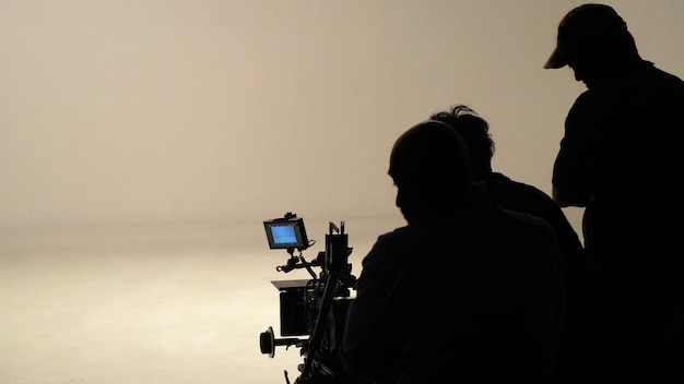 사진 일하는 사람들의 실루엣이나 제작 영화 제작진이 카메라 장비 세트가 있는 스튜디오에서 영화를 만들거나 tv 온라인 콘텐츠 라이브 쇼를 촬영하고 있습니다.