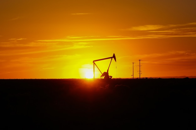 夕焼け空を背景に油田でシルエットオイルポンプ