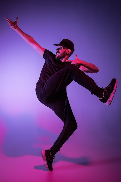 The silhouette of one young hip hop male break dancer dancing on colorful background