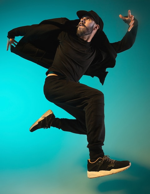 The silhouette of one young hip hop male break dancer dancing on colorful background