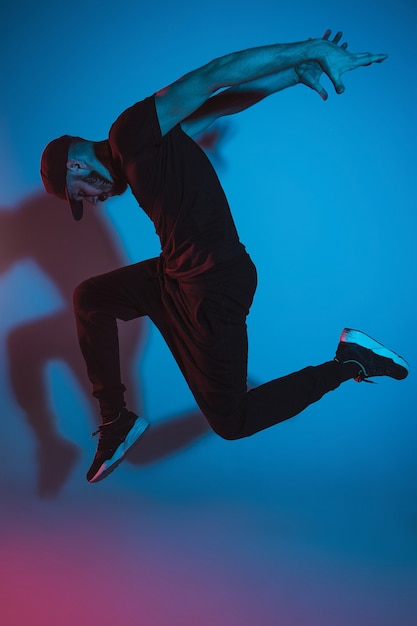 The silhouette of one young hip hop male break dancer dancing on colorful background