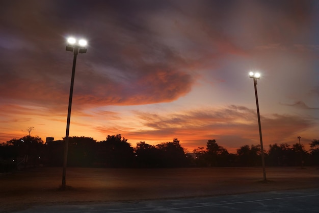 Siluetta del palo della luce all'aperto nel parco sportivo locale vuoto con cielo drammatico al mattino dell'alba