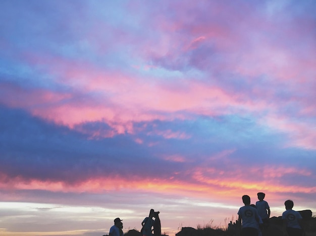 Silhouette of people against cloudy sky during sunset