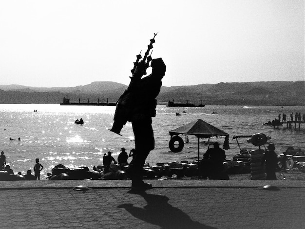 Silhouette people at beach against clear sky