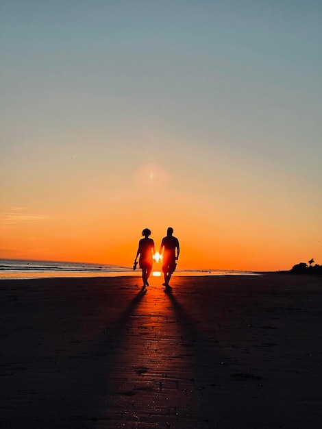 Photo silhouette people on beach against sky during sunset