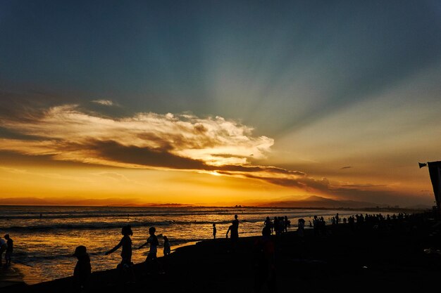 Photo silhouette people on beach against sky during sunset