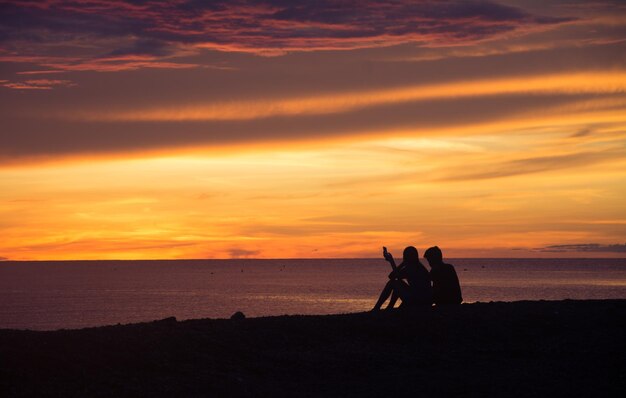 Photo silhouette people on beach against sky during sunset