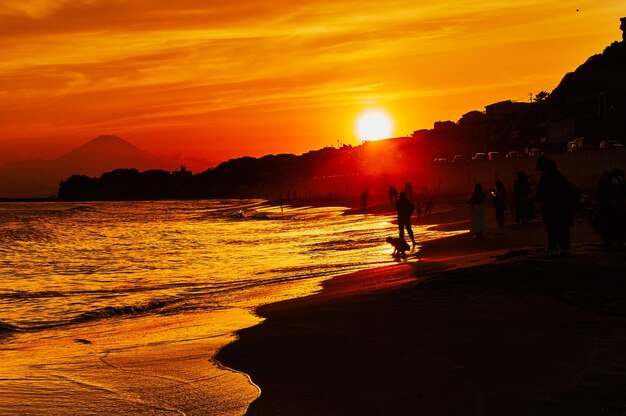 Silhouette people on beach against sky during sunset