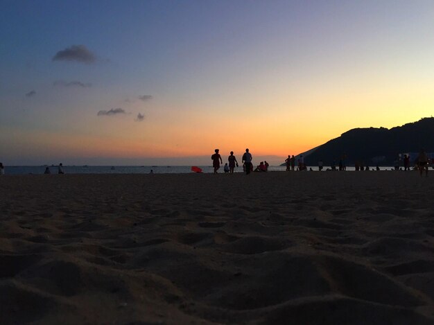 Silhouette people at beach against sky during sunset