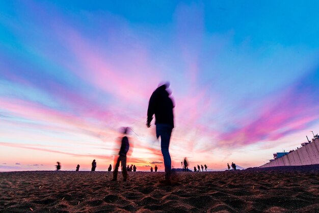 Silhouette people on beach against sky during sunset