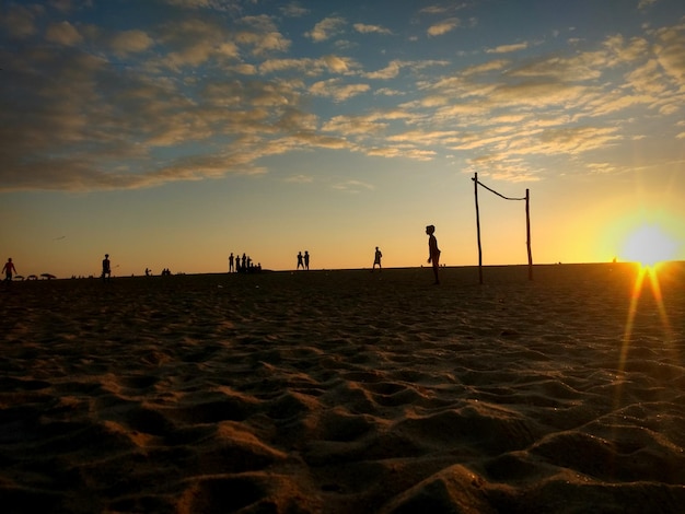 Photo silhouette people at beach against sky during sunset