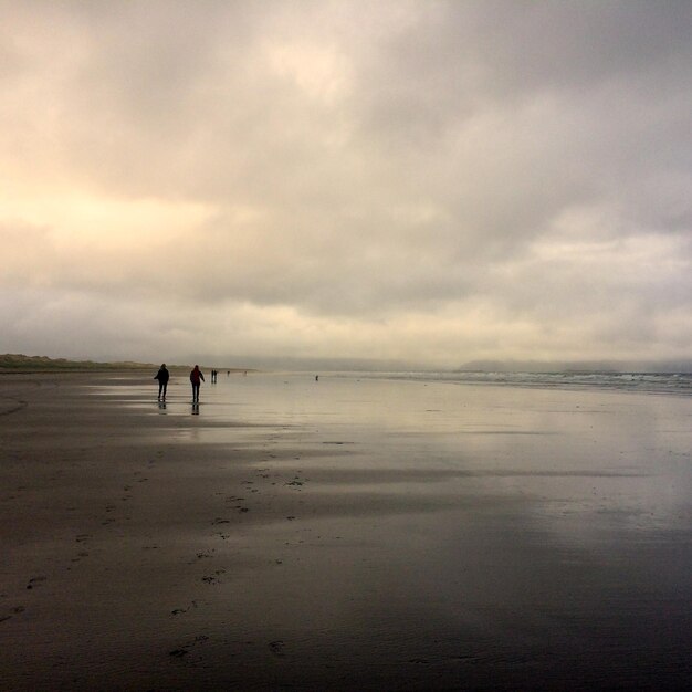 Photo silhouette people on beach against sky during sunset