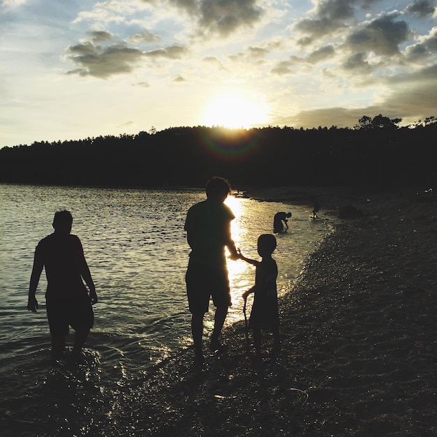 Foto silhouette di persone sulla spiaggia durante il tramonto