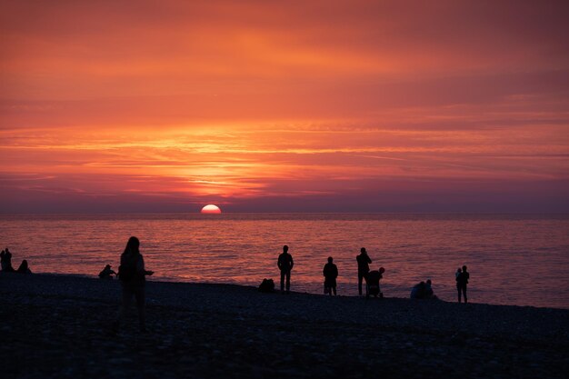 Photo silhouette of people on a beach enjoying the sunset