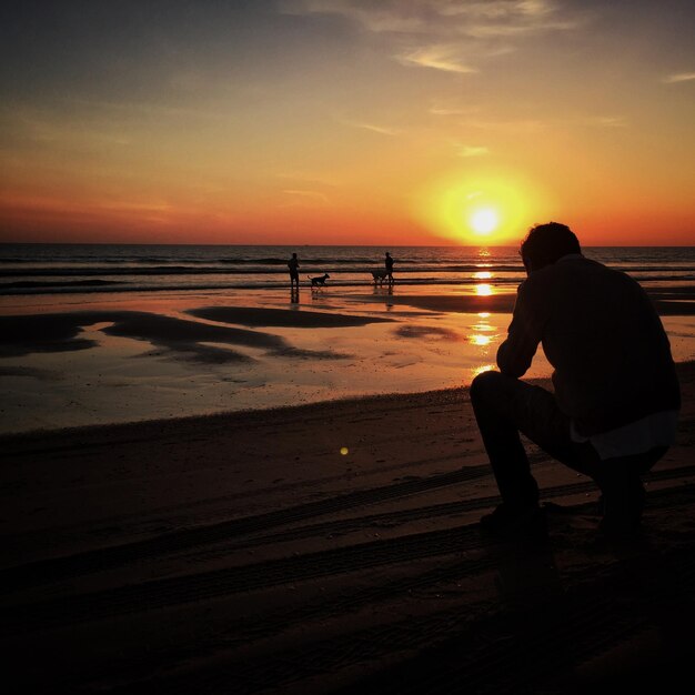 Photo silhouette of people on beach at sunset