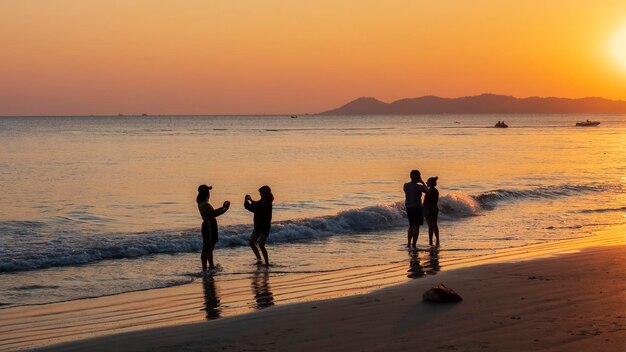 Silhouette of people on the beach with the golden glow of\
sunset in the background