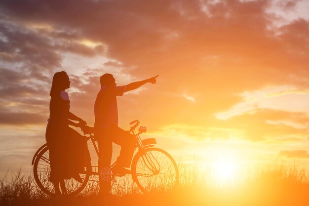 Silhouette people on bicycle during sunset