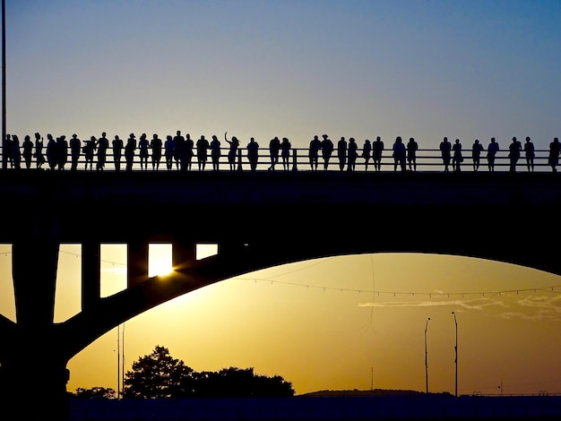 Foto silhouette di persone sul ponte contro un cielo limpido durante il tramonto