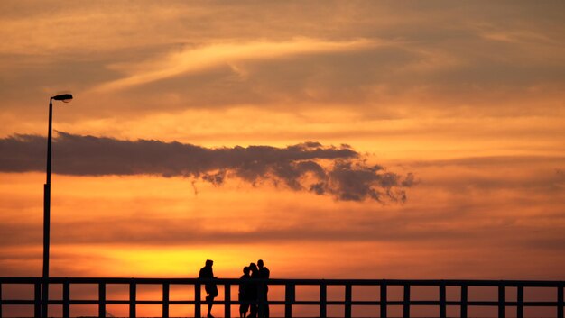 写真 夕暮れのドラマチックな空に照らされた海の人々のシルエット