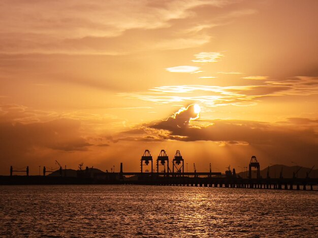 Silhouette people by sea against sky during sunset