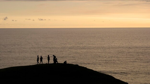 写真 夕暮れの海で人々のシルエット