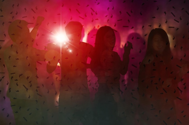 Silhouette of people dancing under falling confetti
