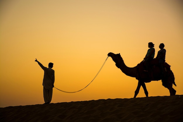 Foto silhouette di persone nel deserto contro un cielo limpido durante il tramonto