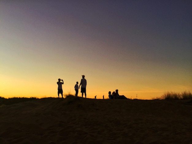 夕暮れの空を背景にフィールドのシルエットの人々