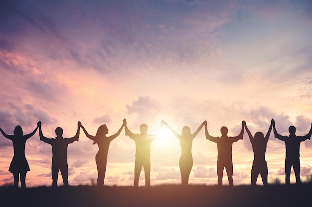 Photo silhouette of people holding hands against sunset background concept of peace and victory