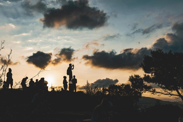 Фото Силуэт людей на суше на фоне неба во время захода солнца