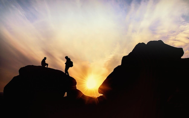 Фото Силуэт людей на скале на фоне неба во время захода солнца