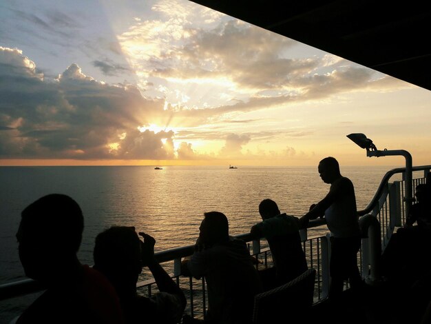 Silhouette people playing on beach against sky during sunset