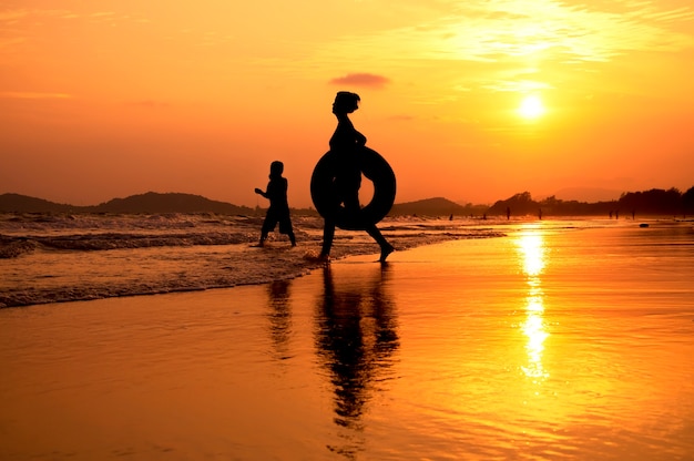 Silhouette di persone che giocano sulla spiaggia al tramonto