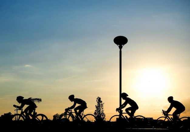 Foto silhouette di persone in bicicletta per strada contro il cielo durante il tramonto