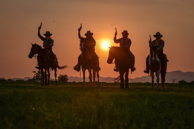 Foto silhouette di persone che cavalcano sul campo contro il cielo durante il tramonto