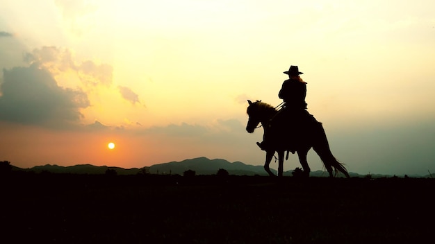 夕暮れの空に向かって馬に乗ったシルエットの人々