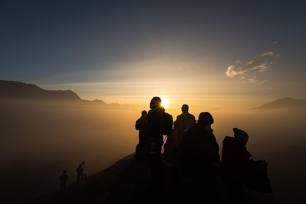 Foto silhouette di persone sulla roccia contro il cielo durante il tramonto