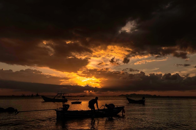 Silhouette people on sea against sky during sunset