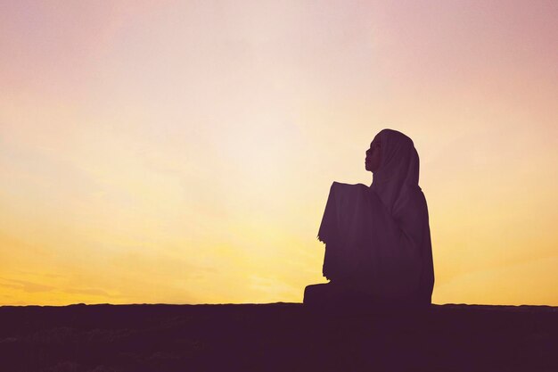 Silhouette people sitting against orange sky