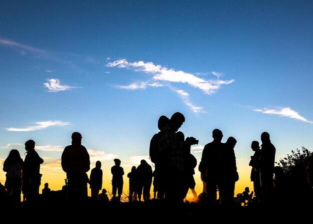 写真 夕暮れの空に向かって立っている人々のシルエット