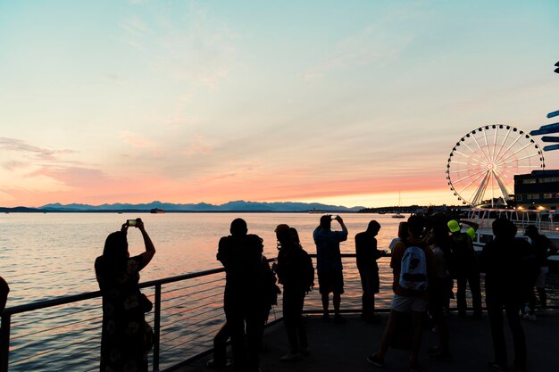 写真 夕暮れの際にビーチに立っているシルエットの人々