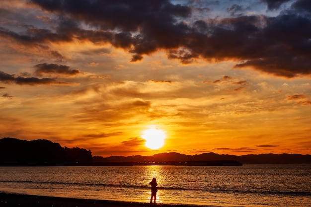 Silhouette people standing on beach against sky during sunrise