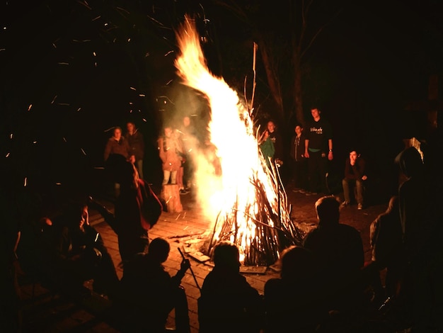 Photo silhouette people standing by bonfire at night