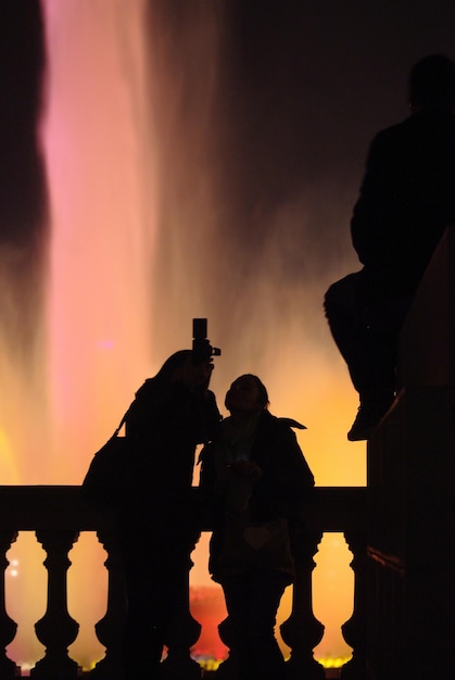 Foto persone a silhouette in piedi vicino alla ringhiera contro la fontana