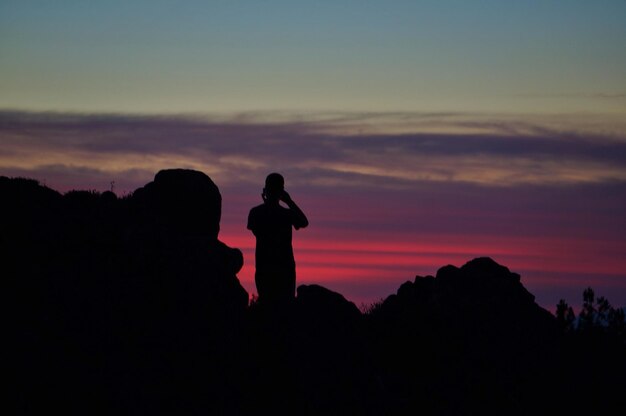 Photo silhouette people standing on cliff against sky during sunset