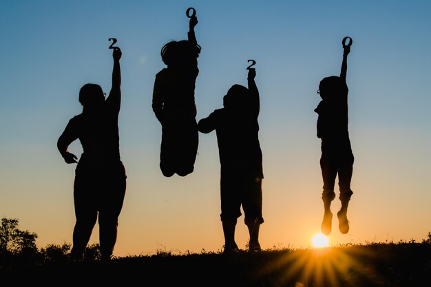 Photo silhouette people standing on field against sky during sunset