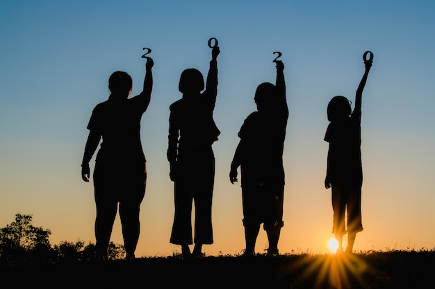 Silhouette people standing on field against sky during sunset